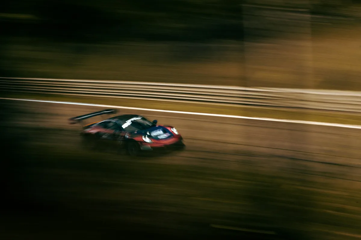 A sports car racing at night, blurred with speed